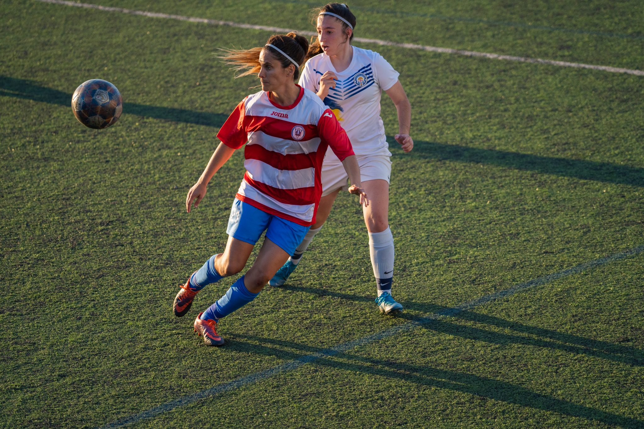 Foto d'unes jugadores de futbol femení en un camp de fútbol. Fotografia realitzada per PinStudio. Productora audiovisual a Barcelona